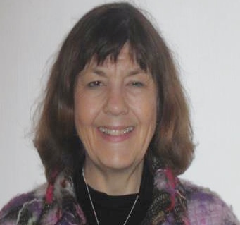 Smiling person wearing patterned jacket and necklace